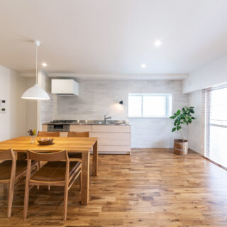 床はナラの無垢材をセレクト。真っ白な空間に有機的な表情がプラスされ、ホッとくつろげるナチュラルな心地よさが生まれている。キッチン周辺の壁はパウダールームとカラートーンを合わせ、濃淡のあるグレーのタイルを採用。こちらも白い空間の上品なアクセントになっている