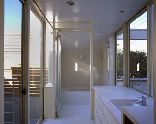 透明ガラスに囲まれた、明るい洗面エリア。浴室（正面）からテラス（右側）に出ることもできる。テラスから見えない左側に洗濯物干し場を配置し、生活感を隠している。中庭には木製のルーバーが取付けられていて外からは見えないようになっている。