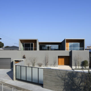 グレーの塗り壁が凛とした表情を見せるY style。大きさの異なる箱を積み重ねたようなモダンなフォルムは、高さ2メートルのコンクリート塀に守られ、外の世界とは一線を画す静謐さだ。