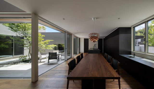 来客の多いライフスタイルに合わせ、ロングサイズのテーブルやパーティー用シンクを備えた機能的な空間に。背面の造作棚には、家電やゴミ箱、さらには神棚までもが美しく収まり、生活感を鮮やかに消し去っている。