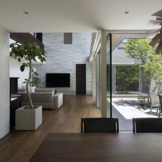 ダイニングキッチンからリビングを見る。リビングのテレビ側の壁は、石を貼ることでアクセントをつけた。