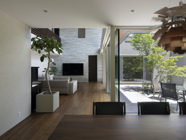 ダイニングキッチンからリビングを見る。リビングのテレビ側の壁は、石を貼ることでアクセントをつけた。