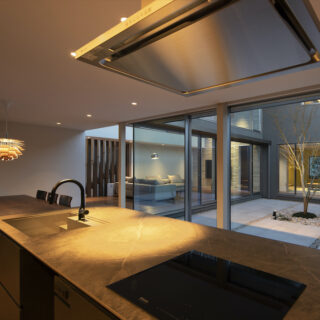 中庭の景色を見ながら作業ができるアイランドキッチン。グレーのシンクとセラミック天板を組み合わせたキッチンは、大場さんと奥様が二人三脚で作り上げた唯一無二の逸品だ。