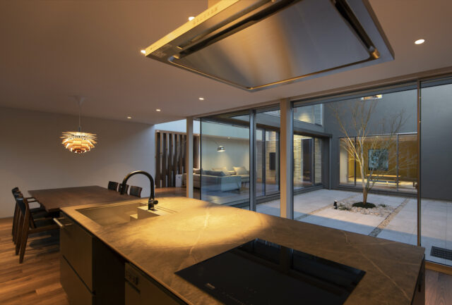 中庭の景色を見ながら作業ができるアイランドキッチン。グレーのシンクとセラミック天板を組み合わせたキッチンは、大場さんと奥様が二人三脚で作り上げた唯一無二の逸品だ。