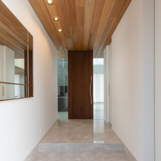 豊かさを感じる、広い玄関ホール。天井の木板と大理石調のタイルがリビングまで続く