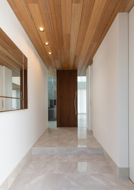 豊かさを感じる、広い玄関ホール。天井の木板と大理石調のタイルがリビングまで続く