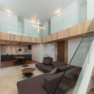 圧倒的な開放感を得られる36.8畳のLDK。5.5ｍの吹き抜けと、ガラス製手摺の効果が大きい。2階の廊下部分にはダイニングの天井と同じ木材を使用。統一感と空間の変化を感じられる