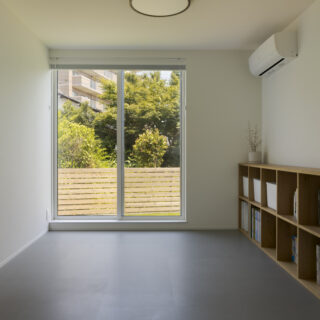 1階寝室は、将来2部屋に分けることができる。将来、車いすが必要になった場合などに備えて1階のどこかは掃き出し窓にしたかったと2人。庭のフェンスは宏昌さんがDIYした。1階は全体的に同じフロアタイルを敷き、設えの雰囲気アップとコストダウンを同時に実現