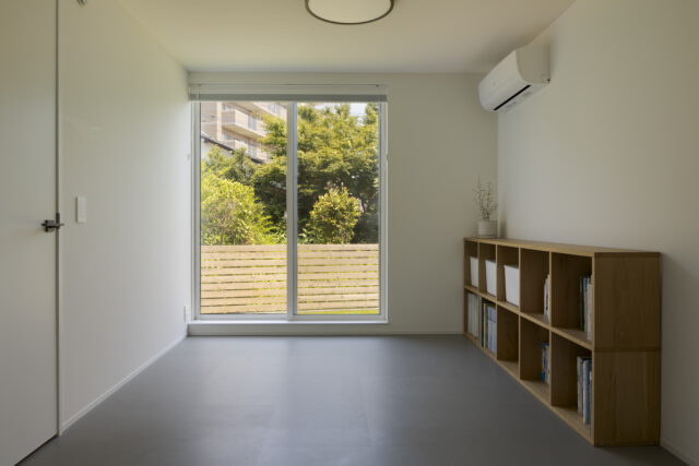 1階寝室は、将来2部屋に分けることができる。将来、車いすが必要になった場合などに備えて1階のどこかは掃き出し窓にしたかったと2人。庭のフェンスは宏昌さんがDIYした。1階は全体的に同じフロアタイルを敷き、設えの雰囲気アップとコストダウンを同時に実現