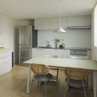 2階キッチン、ダイニング。キッチンは既製品を採用。リビングの棚やダイニングのテーブル、照明は色味や素材感をリフレインさせ、調和が取れた空間を実現。画像左の収納を兼ねたカップボードは奥行きが広め。使いやすく、物もたくさん仕舞えて安心感がある