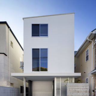 年月を重ねても目地が出ないよう、２・３階は下地にモルタル塗りを採用し、その上から塗装を施した外観。四方に回した廂下の空間を有効利用するため、複数ある室外機はすべて上階に設置している