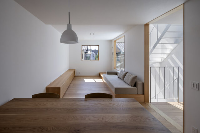 折上天井による縦への広がりや階段室との緩やかなつながりによって、面積以上のゆとりを感じられるリビング。TVボード・ソファ・ダイニングテーブルいずれも造作で設えた
