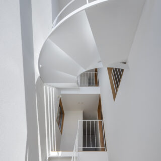 3層吹抜けの階段室は、余白を大切に設計した最もシンボリックな空間。直線と曲線を組み合わせた鉄骨階段が、空間の意匠性を支える大きな役割を果たしている