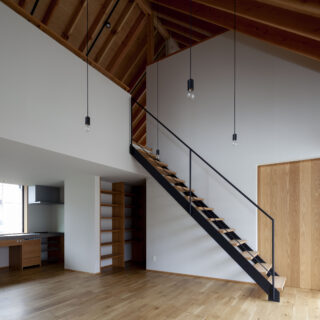 1階LDK。ダイナミックな勾配天井や、連続する垂木の美しさを堪能できる。写真中央、階段を上がった白壁の向こうは2階の子ども部屋で、天井際の一部はガラスを入れてある。明かりなどの気配が伝わり、美しく並ぶ垂木も途切れずに見える