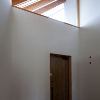 玄関土間の上部は、高い位置から光を採り込む三角窓。邸内から外まで連続する垂木も見える
