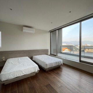 落ち着いた雰囲気をもつ寝室にも大きな窓が。遠くの景色まで見渡せる。