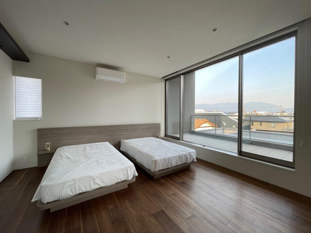 落ち着いた雰囲気をもつ寝室にも大きな窓が。遠くの景色まで見渡せる。