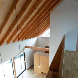 吹抜けは壁で仕切らず1～2階の一体感を演出。手すり壁も上部は木板を浮かせたデザインにして圧迫感を軽減