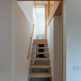 １階奥から、壁伝いに半階上った先にあるのがトイレと洗面コーナー。寝室からもリビングからも半階分の移動で済む抜群のゾーニング。上階からの光が降りてくるよう、階段はスケルトンに。