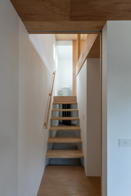 １階奥から、壁伝いに半階上った先にあるのがトイレと洗面コーナー。寝室からもリビングからも半階分の移動で済む抜群のゾーニング。上階からの光が降りてくるよう、階段はスケルトンに。