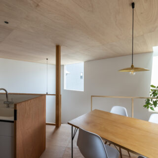 キッチンは、奥様のリクエストにより、人造大理石のシステムキッチンを採用。ラワン材のパネルで囲うことにより、造作の背面収納との統一感を出した。下にいる子どもたちの様子を見ながら料理や洗い物ができる。