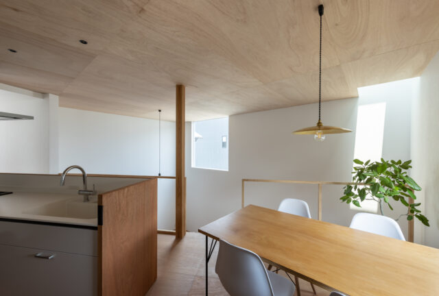 キッチンは、奥様のリクエストにより、人造大理石のシステムキッチンを採用。ラワン材のパネルで囲うことにより、造作の背面収納との統一感を出した。下にいる子どもたちの様子を見ながら料理や洗い物ができる。