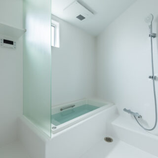 バスルームは変形したこの家の形状に合わせてFRP仕上げで造作。掃除のしやすさやコストカットを兼ね、あえて扉を設けず、シャワーカーテンを採用した。脱衣スペースも防水仕様のFRP仕上げで一体的に造作している。