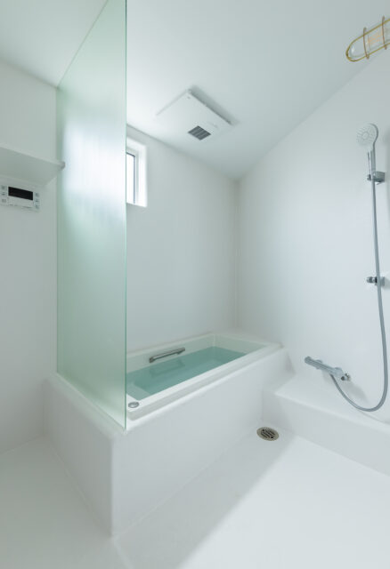 バスルームは変形したこの家の形状に合わせてFRP仕上げで造作。掃除のしやすさやコストカットを兼ね、あえて扉を設けず、シャワーカーテンを採用した。脱衣スペースも防水仕様のFRP仕上げで一体的に造作している。