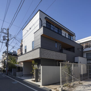 外観。2つの世帯のエリアが外壁で色分けされ、感覚的に二世帯住宅だとわかるデザイン。そのうえで1階・2階をつなぐ部分に帯状のアクセントウォールを通し、2つの世帯が1つの建物の中にあることを印象付けさせた