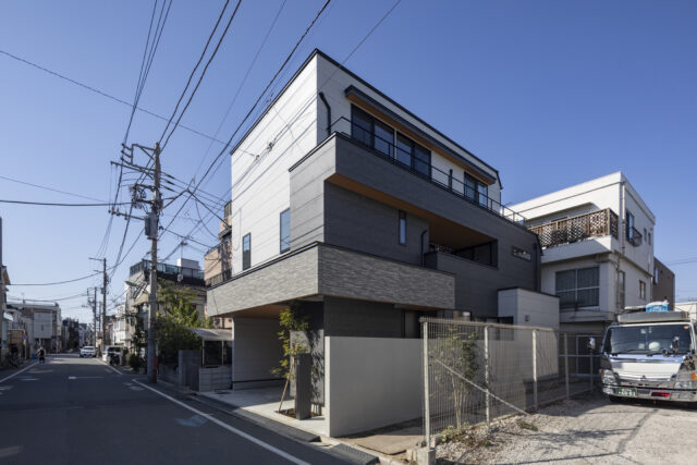 外観。2つの世帯のエリアが外壁で色分けされ、感覚的に二世帯住宅だとわかるデザイン。そのうえで1階・2階をつなぐ部分に帯状のアクセントウォールを通し、2つの世帯が1つの建物の中にあることを印象付けさせた